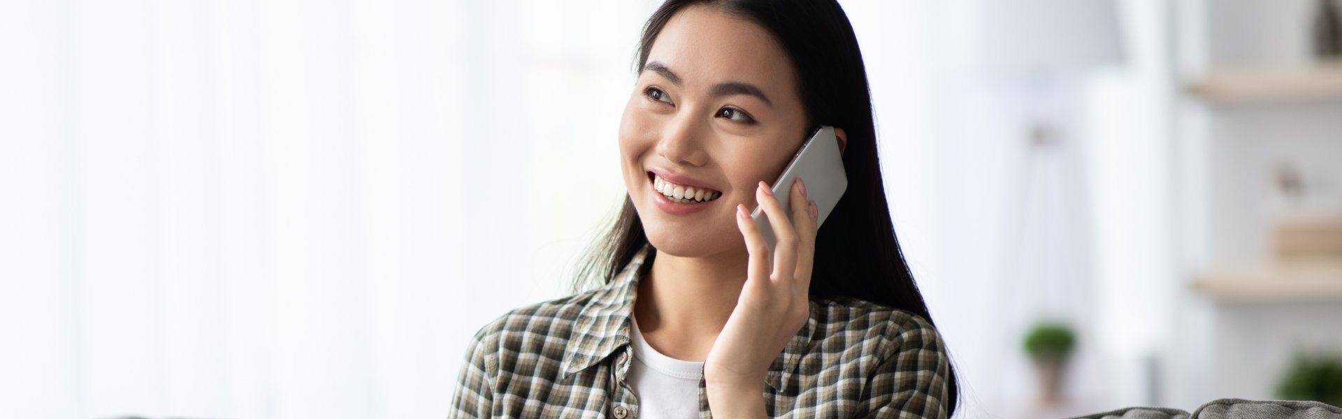 Pretty young woman having phone conversation, using laptop